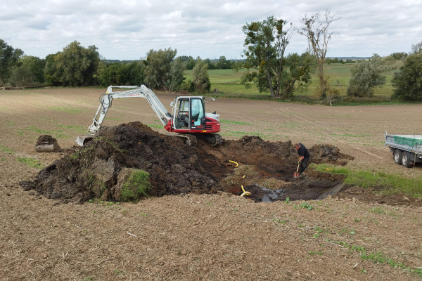 Backer auf einem Acker der ein Loch aushebt