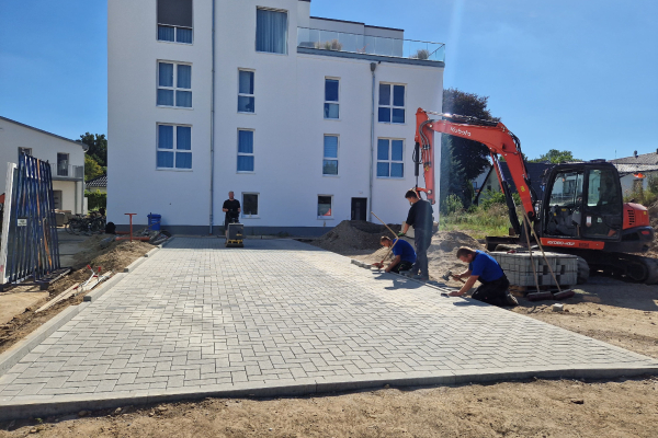 Gepflasterter Parkplatz wird angelegt vor einem Mehrfamilienhaus - Neubau